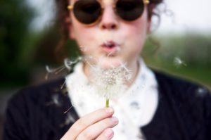 Woman blowing a dandelion flower